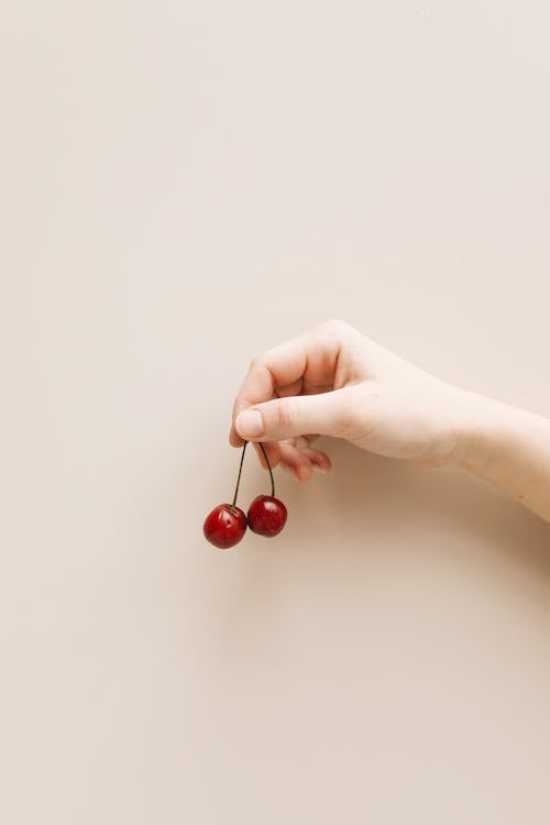 Photo of a Person's Hand Holding Cherries