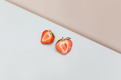 Free Simple close-up of a halved strawberry on a pastel surface, ideal for food concepts. Stock Photo