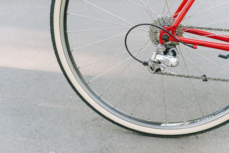 Detailed close-up of a red bicycle wheel and gear mechanism on pavement.
