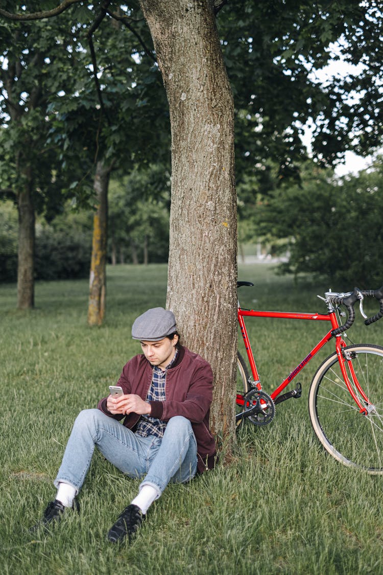 Man Using His Smartphone While Sitting Under The Tree 