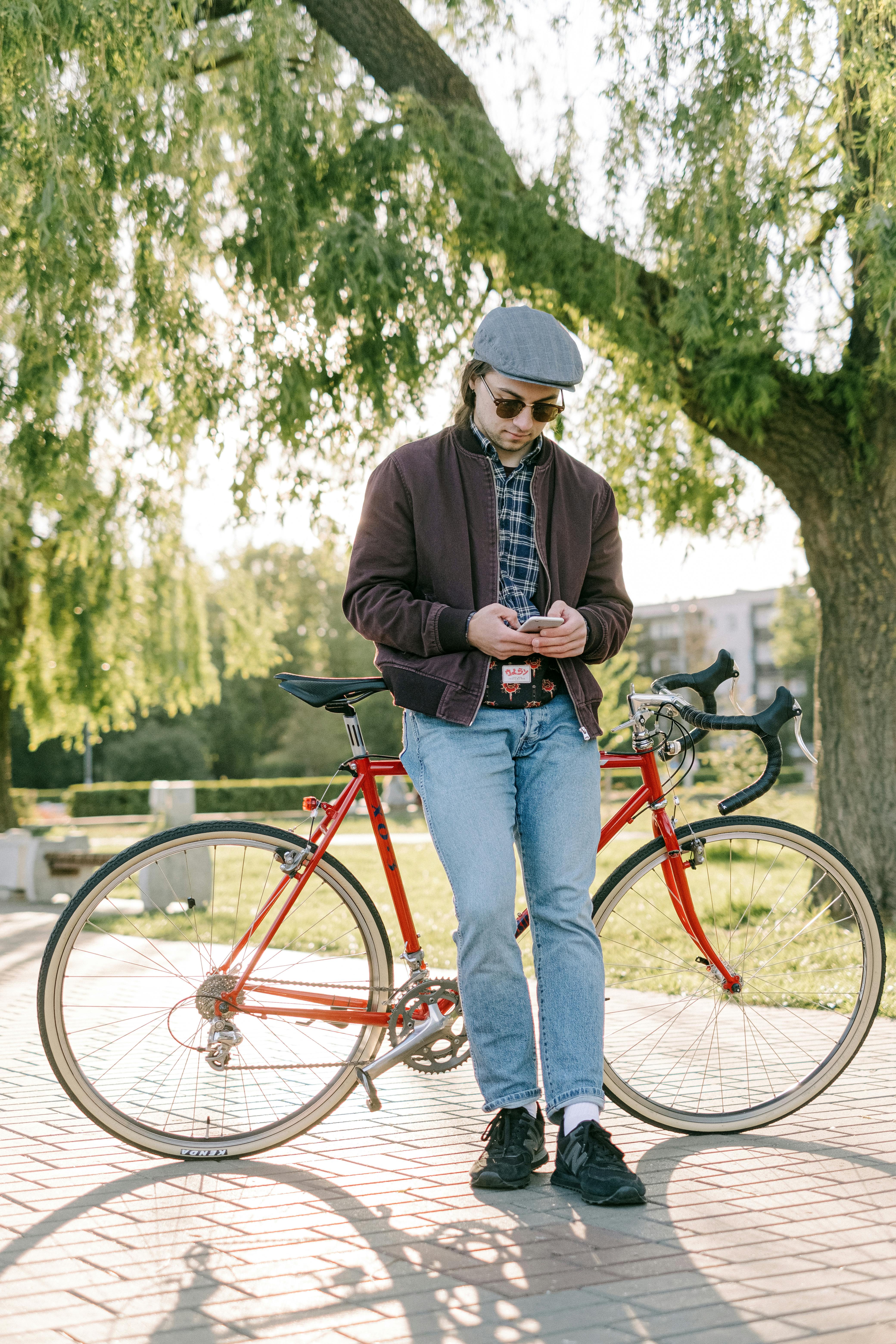 photo of a man using his cell phone while leaning on his bicycle