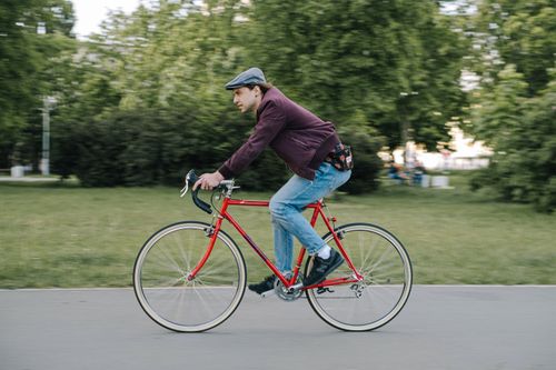 Free A man wearing a beret rides a red bicycle outdoors on a sunny day. Stock Photo