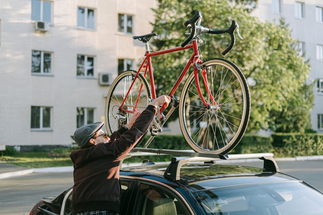 Person in Brown Jacket and Black Pants Standing Beside Red Bicycle