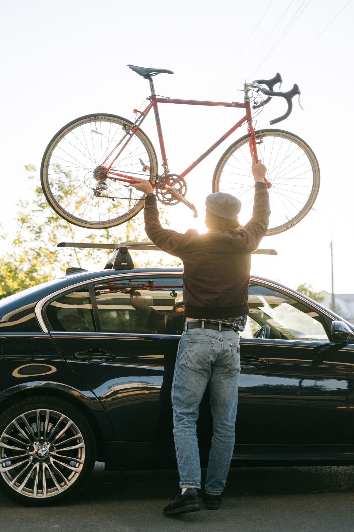 Person loading bicycle onto vehicle hitch-mounted bike rack at sunset for adventure travel transport