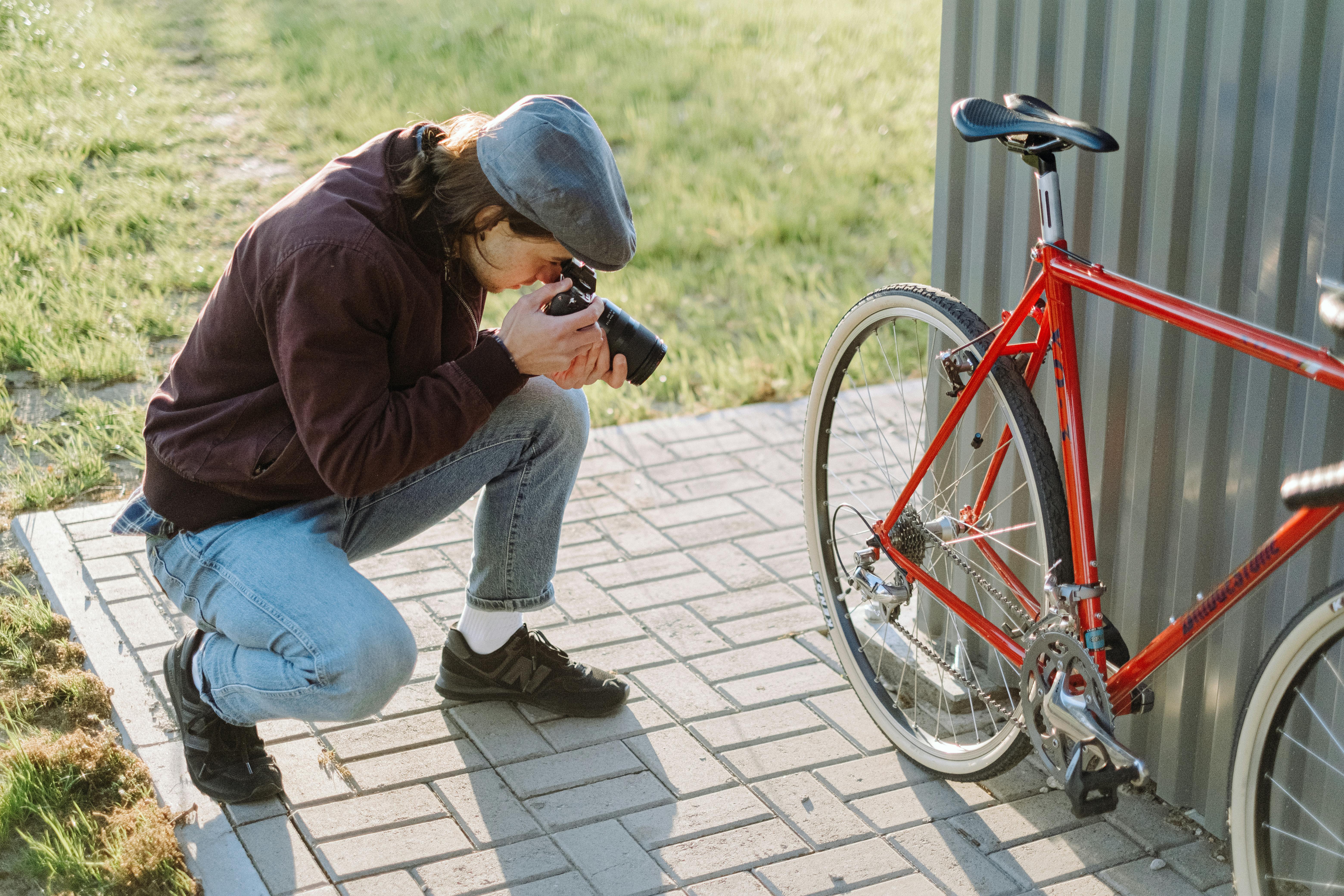 Photo of a Man with a Beret Cap Taking a Photo of a Bicycle Free