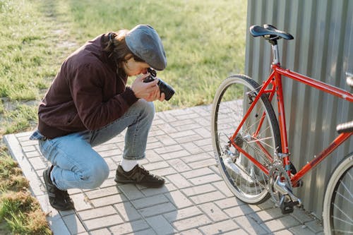 Photo of a Man with a Beret Cap Taking a Photo of a Bicycle
