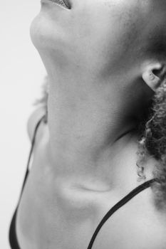 Artistic monochrome close-up depicting a woman's neck and chin with soft lighting.