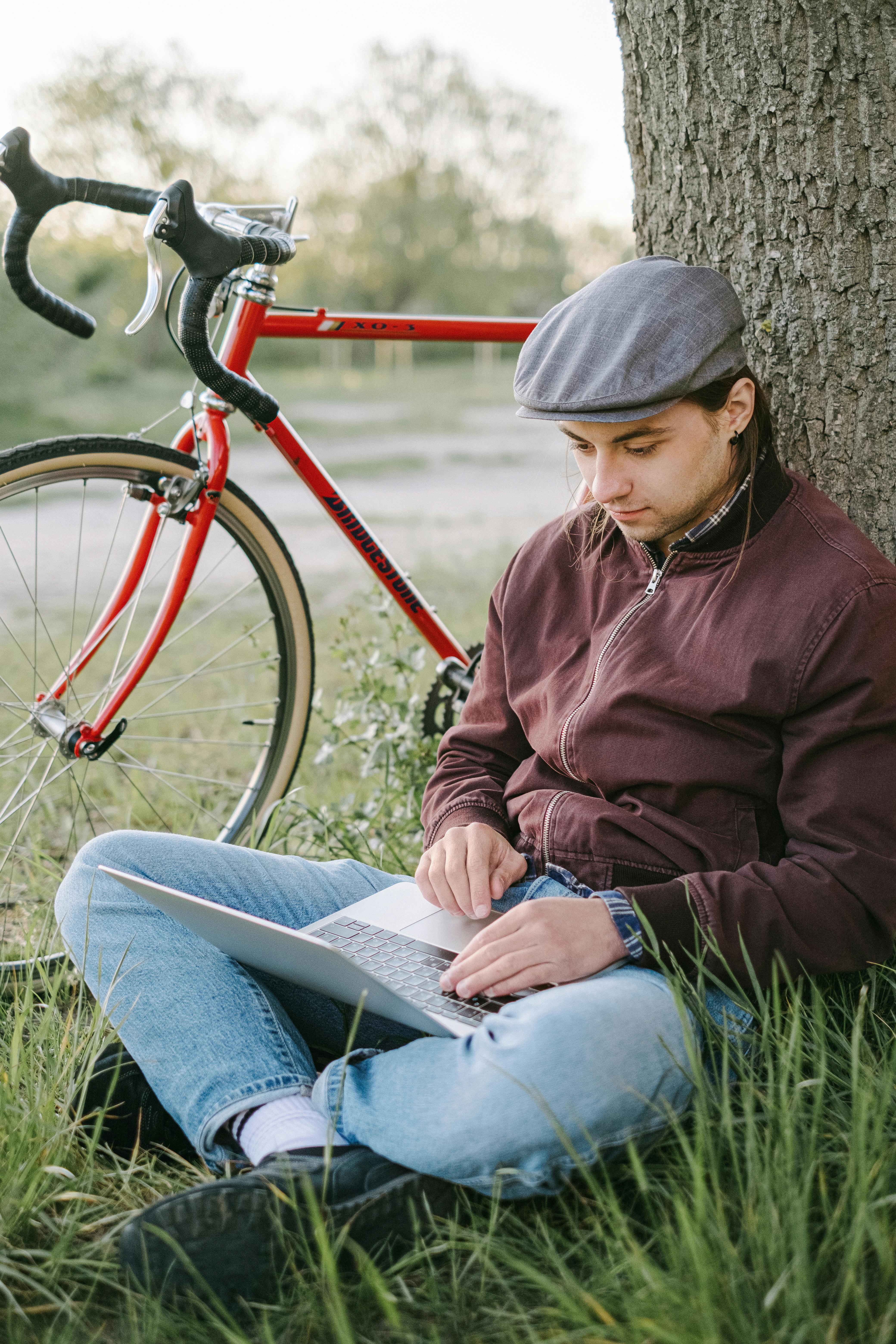 man sitting under a tree and working on his laptop