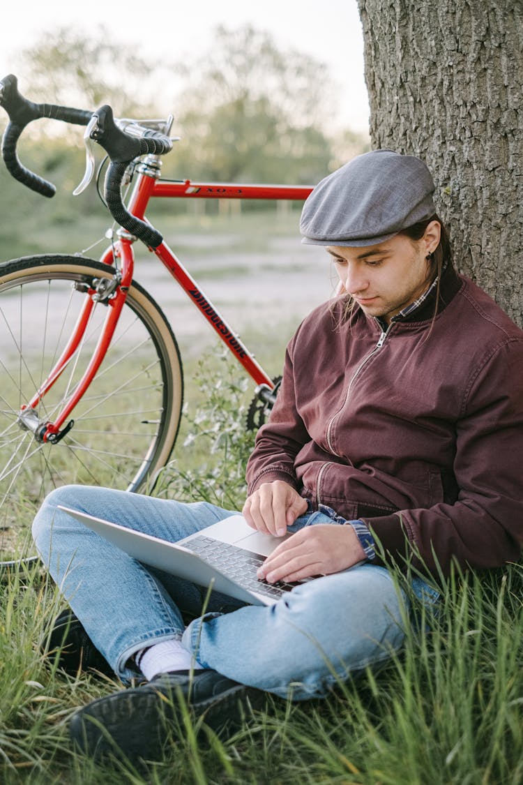 Man Sitting Under A Tree And Working On His Laptop