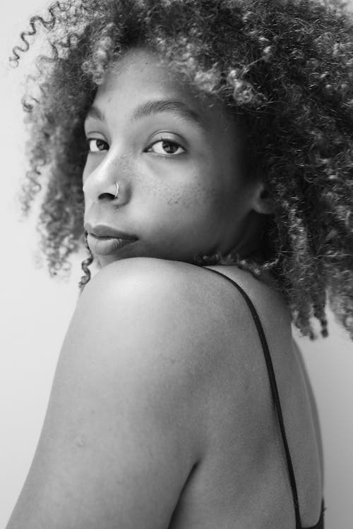 Grayscale Photo of a Woman with Curly Hair Looking over her Shoulder