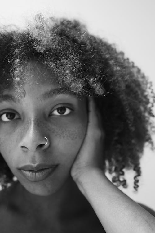 Grayscale Photo of a Woman with Curly Hair and a Nose Piercing