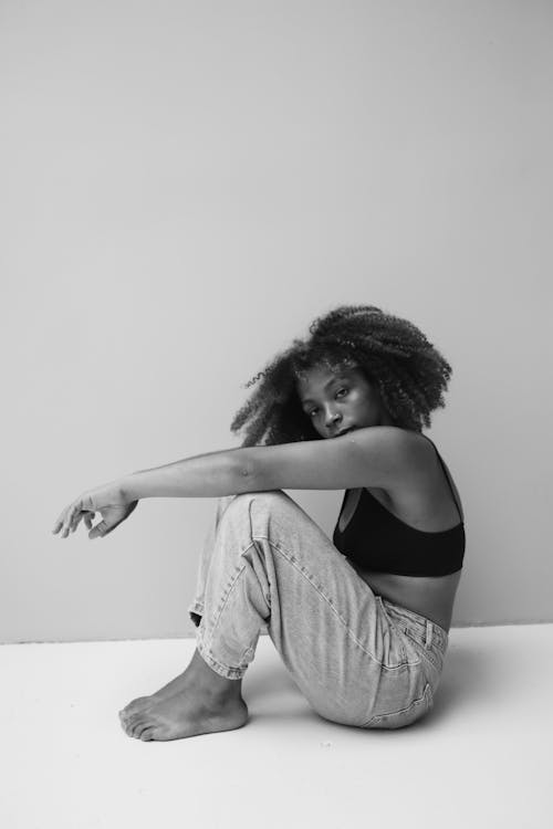 A Woman in a Black Bra and Denim Jeans Sitting on the Floor