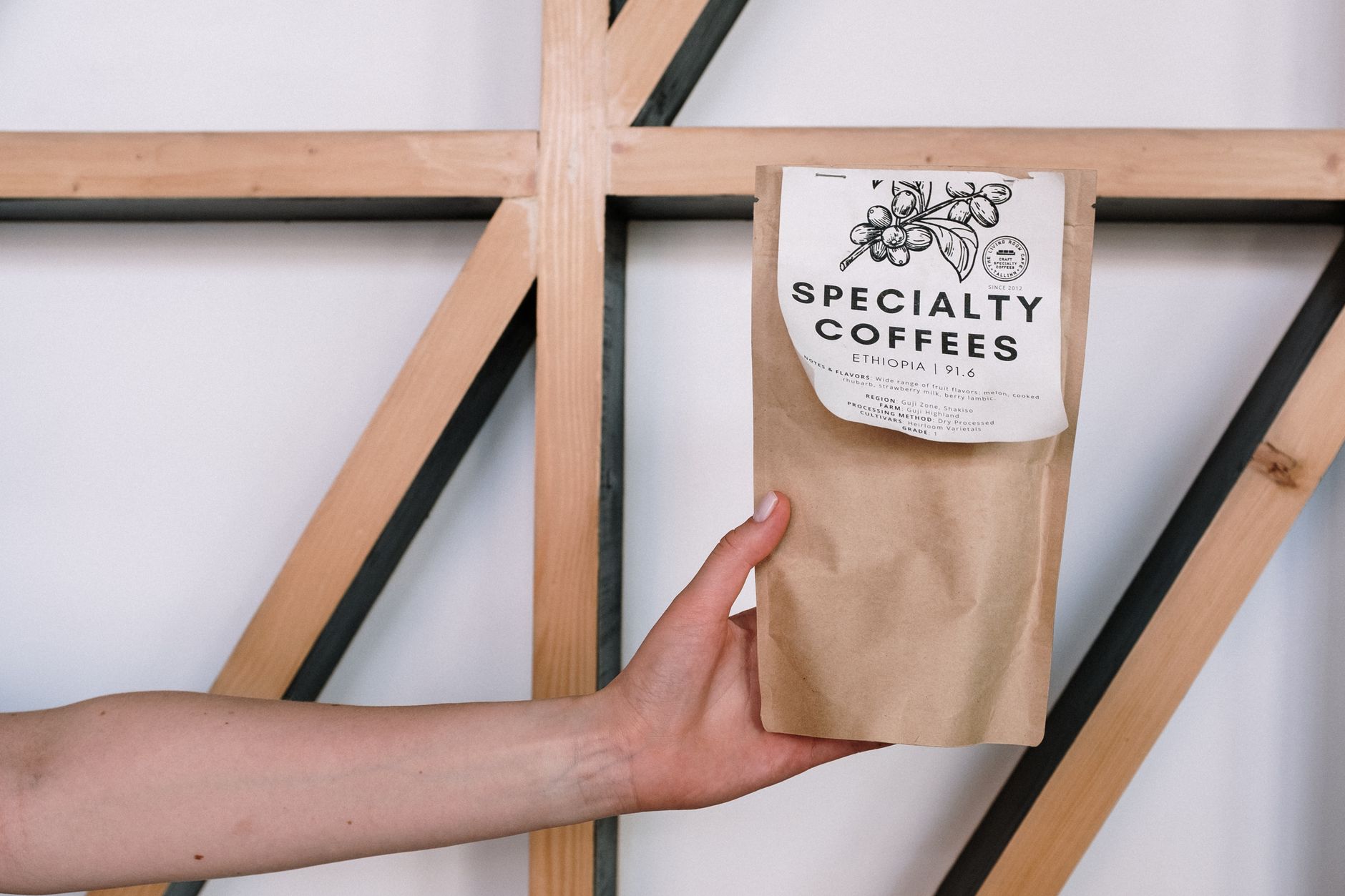 A hand holding a specialty coffee package against a minimalist background with wooden beams. What Is Single Origin Coffee?