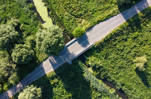 Free Aerial photo of a road cutting through lush greenery and waterway. Stock Photo