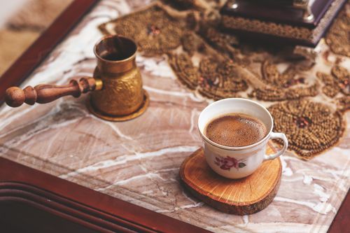 Free A cozy rustic setting featuring a ceramic cup of coffee on a decorative table. Perfect for lifestyle themes. Stock Photo