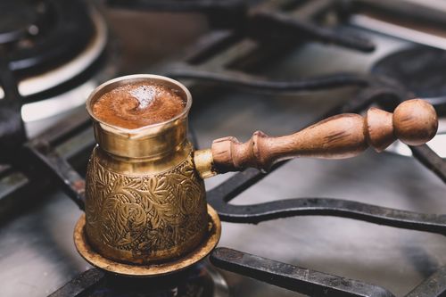 Free Close-up of traditional Turkish coffee brewed in a cezve on a stove with intricate design. Stock Photo
