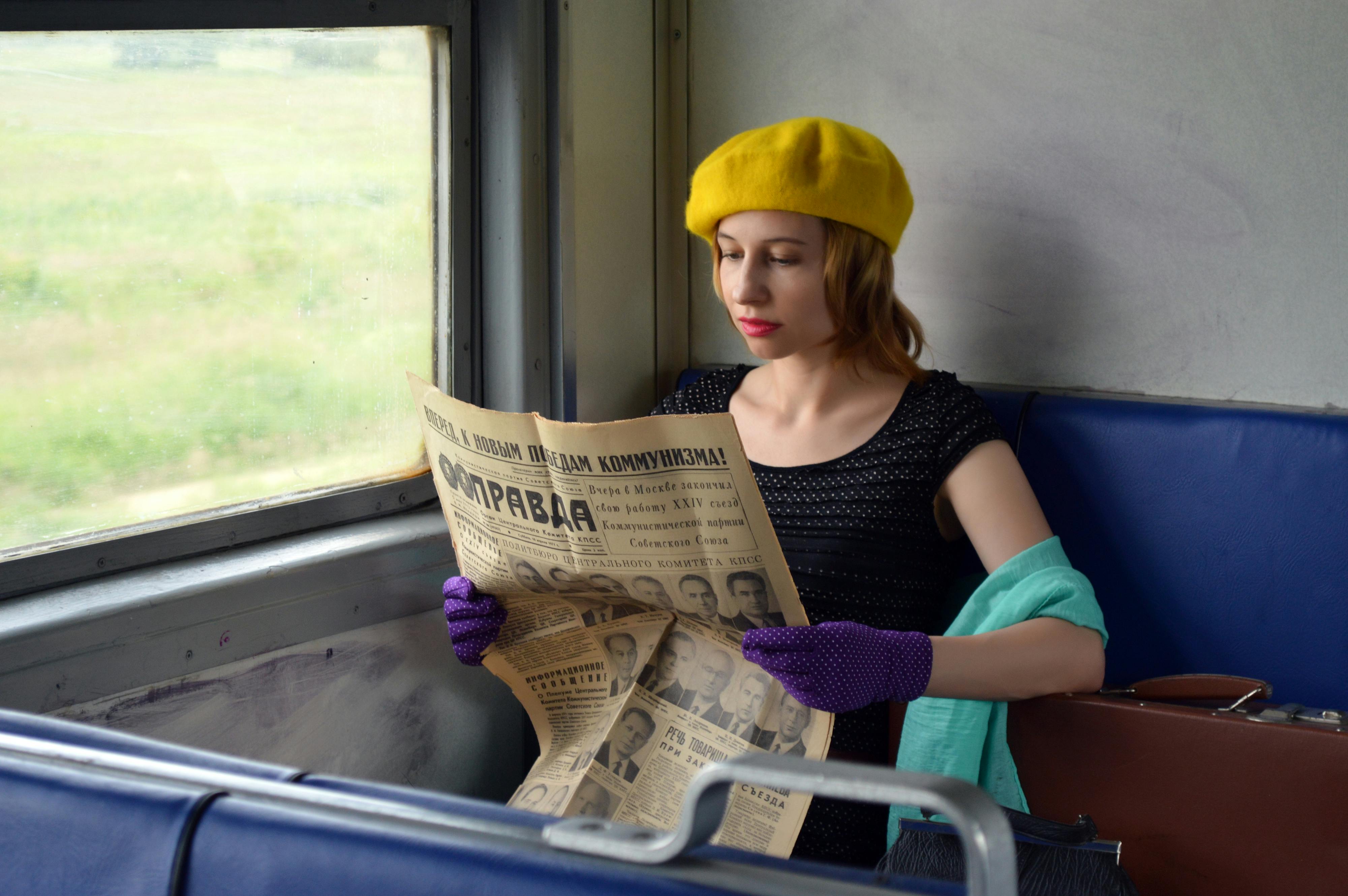 young woman reading old newspaper in train