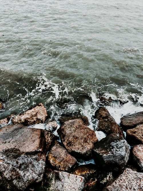 Free High angle view of foamy waves washing big rough stones on coast at daytime Stock Photo
