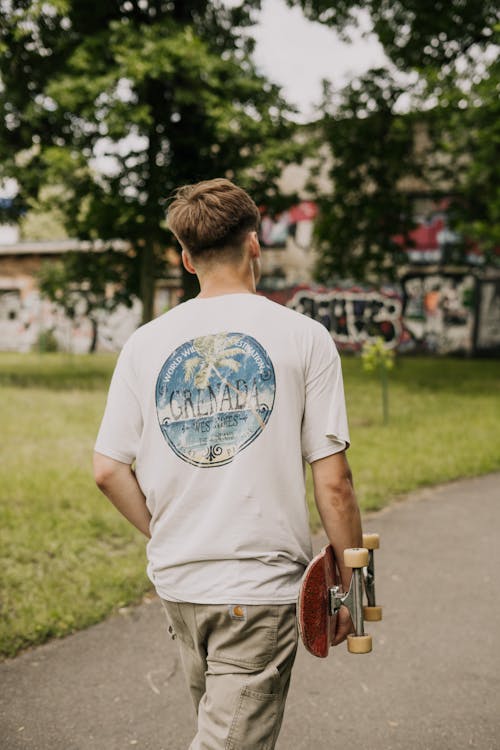 Backview Photo of Man Carrying Skateboard