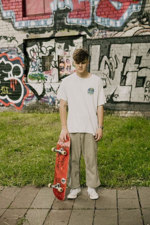 Free Teenager with skateboard by vibrant graffiti wall showcasing urban street culture. Stock Photo