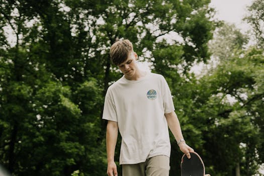 年轻人站在绿色公园的滑板上沉思