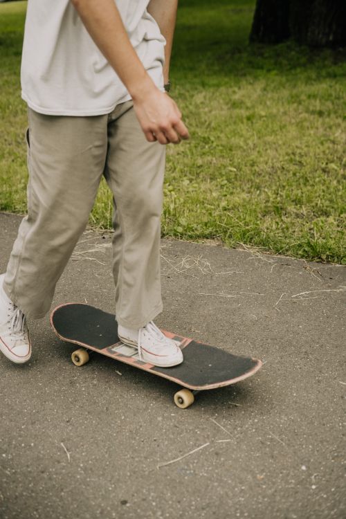 Free A teenager skateboarding on a paved path surrounded by greenery, capturing the thrill of outdoor activities. Stock Photo