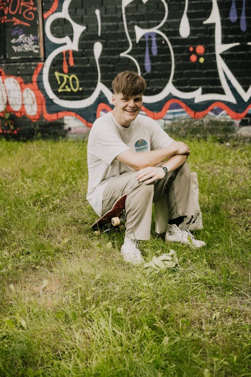 Free A Happy Young Man Sitting on the Grass Stock Photo