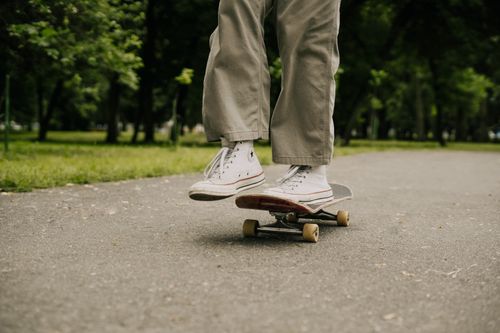 Free Close-up of a skateboarder's feet performing a trick in a sunny park setting. Stock Photo