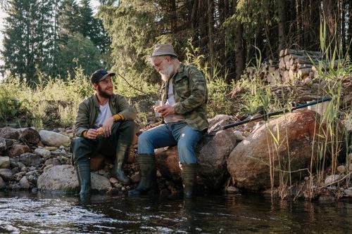 Free Two men enjoying a peaceful fishing day by the riverside in nature. Stock Photo
