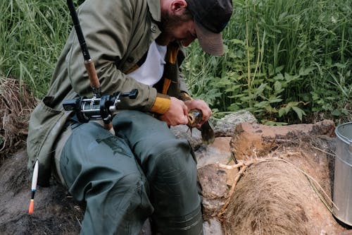 Man in Gray Jacket and Black Pants Holding Black and Gray Fishing Rod