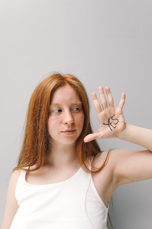 Free Woman in White Tank Top with Written Word on Her Left Hand Stock Photo