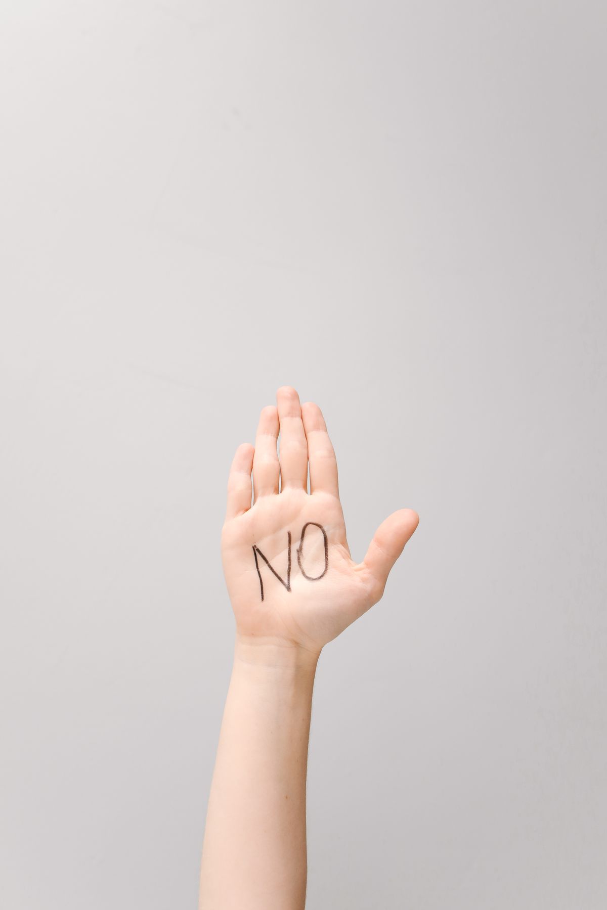 Abgrenzung: Erhobene Hand mit dem Wort „Nein“ auf der Handfläche