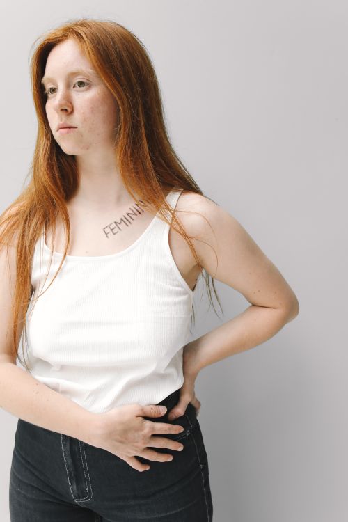 Free Confident young woman with red hair stands expressing a feminism message on her shoulder. Stock Photo