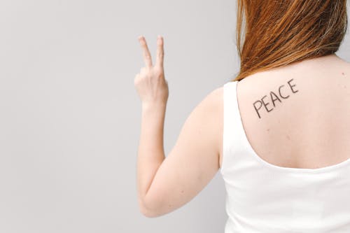 A Woman in White Tank Top Doing Peace Sign
