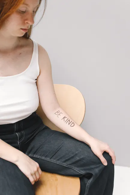 Femme assise avec un tatouage éphémère en lettrage sur l'avant-bras, look casual et naturel