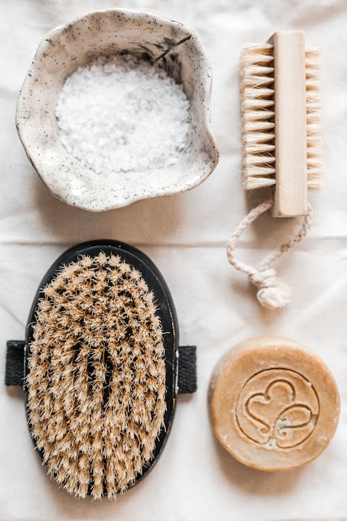 Free Top view of flat lay with wooden brooches  and organic soap and sea salt in ceramic bowl placed on fabric surface Stock Photo