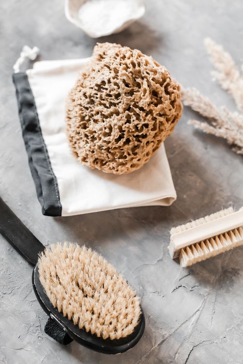 Free From above of eco friendly pumice and brush for body and little double sided wooden brush placed on gray surface Stock Photo