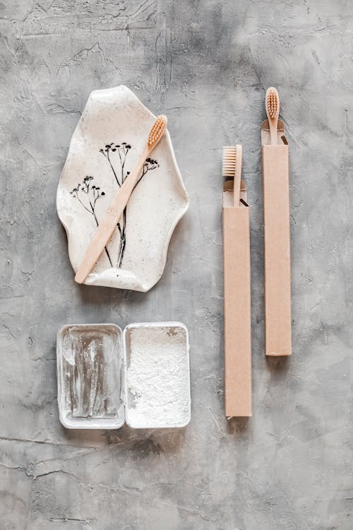 Top view arrangement of bamboo toothbrushes and tooth powder placed on gray marble table