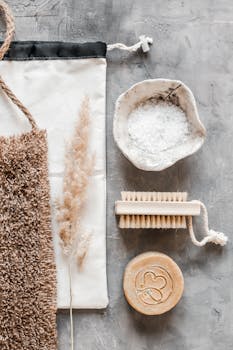 Top view arrangement of eco friendly bamboo body brush soap bath salt and bast wisp placed on gray marble surface