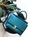Top view trendy elegant dark blue handbag placed on stool near copybook and eyeglasses in light room