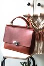 Voguish brown leather purse in modern design placed on stool in light living room