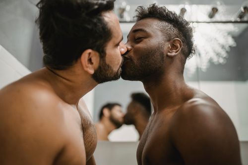 Free A loving kiss between two shirtless men, reflecting their affection and bond. Stock Photo