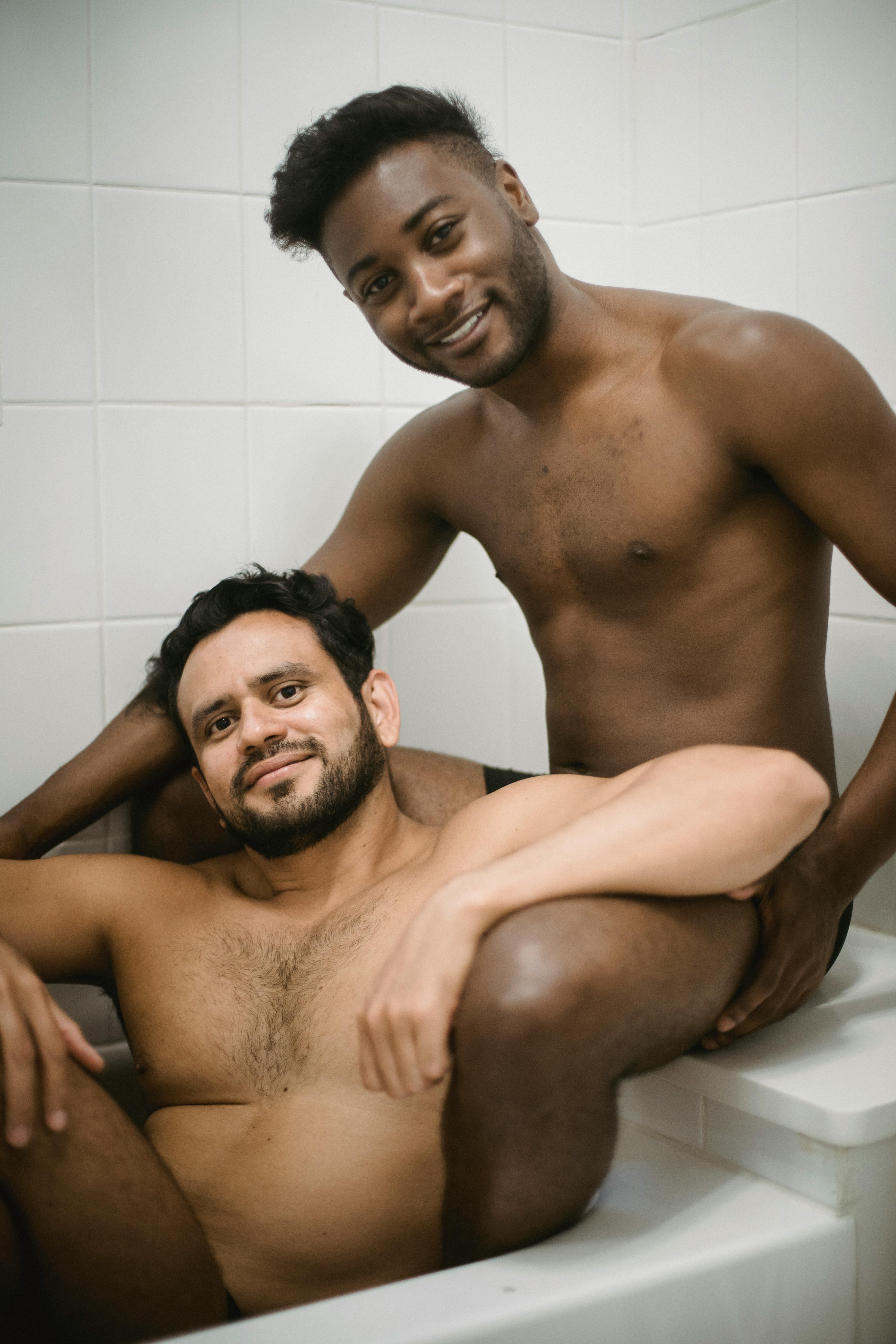 two men sitting naked in a bathtub