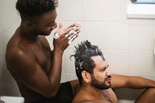 Free Intimate moment of a couple enjoying a playful shower routine together at home. Stock Photo