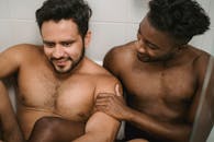 Topless Man Sitting on White Ceramic Bathtub