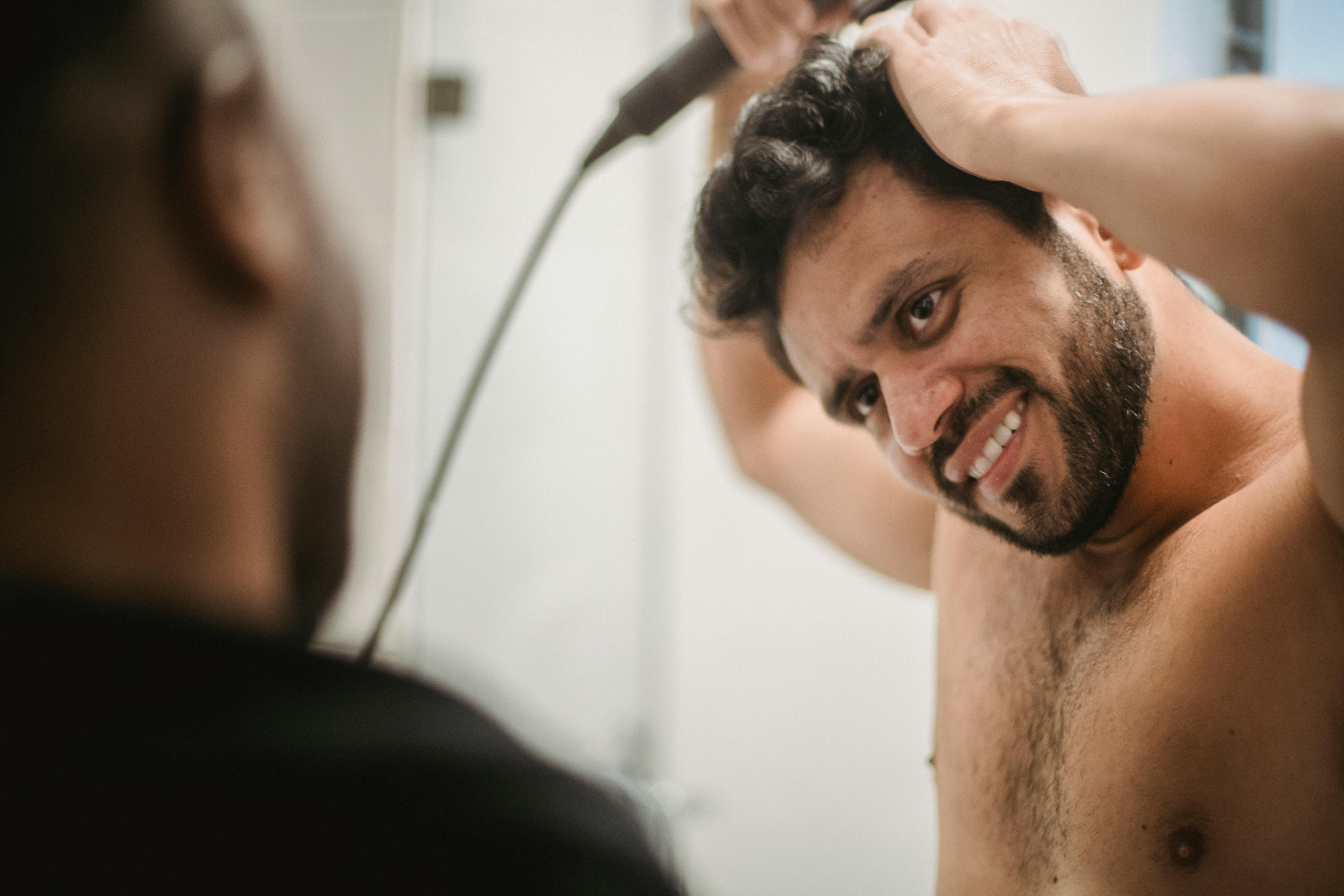 smiling young man blow drying hair