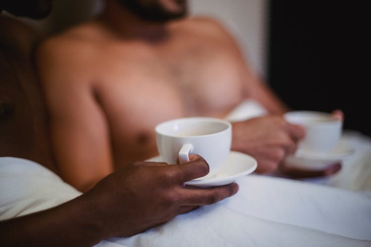 Close-up Of Couple Drinking Coffee In Bed