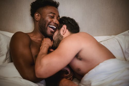Free Photo of a Shirtless Man Laughing on the Bed Stock Photo