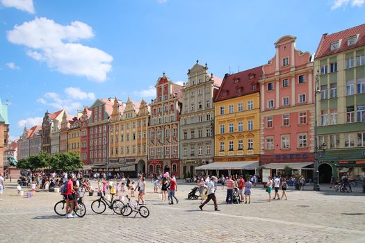 Lively town square with colorful facades, bicycles, and people enjoying a sunny day.