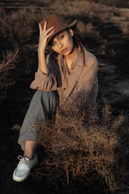 Free Woman in Brown Button Up Shirt Sitting on Brown Grass Stock Photo